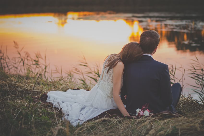 wedding-couple-sitting-on-green-grass-in-front-of-body-of-70737-(1).jpg